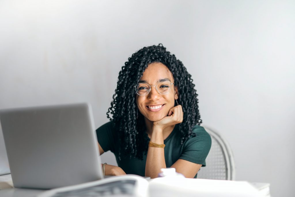 Stock image of a lady smiling whilst doing business writing training at her laptop